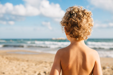 Back view of topless kid on beach