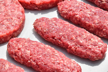 Raw red meat long kebabs, cutlets on parchment