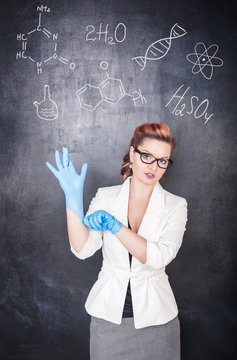 Chemistry teacher in gloves on blackboard background