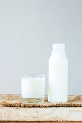 A glass of rustic milk and bottle of rustic milk on a wood table