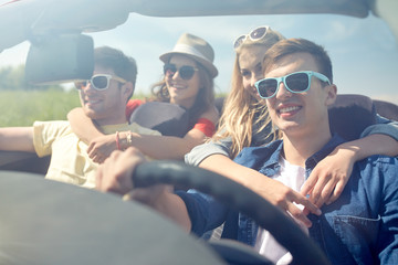happy friends driving in cabriolet car outdoors