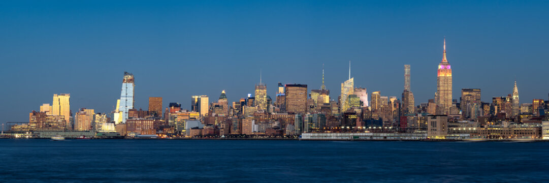 Panoramic view at dusk of Manhattan Midtown West and illuminated skyscrapers with the Hudson River. New York City