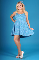 Beautiful young girl posing in street clothes on blue background.Isolated studio portrait