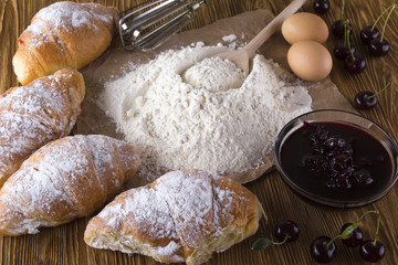 fresh croissant with flour, cherry jam, handle mixer and eggs.
