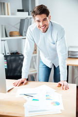 Smiling young businessman working with documents at workplace