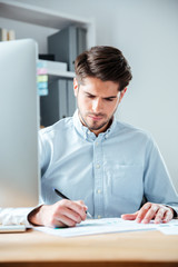 Confident businessman sitting at the table and signing document