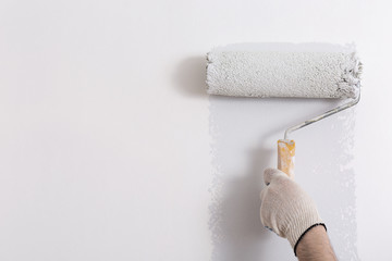 Close up of painter hand painting a wall grey with paint roller