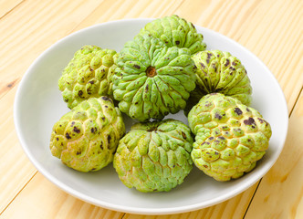 custard apple fruit on white plate with wood background