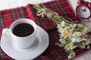 Cup of coffee,chamomile and alarm clock.
