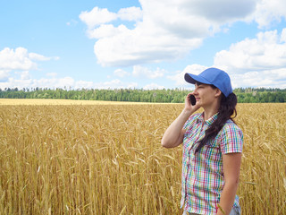 Young pretty farmer girl standing in yellow wheat field and talk