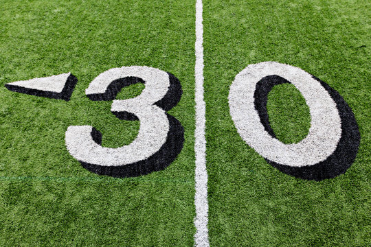 30 yard line on a green football field with white lettering
