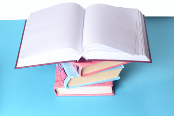Open book, stack of colorful hardback books on light table. Back to school. Copy space for text