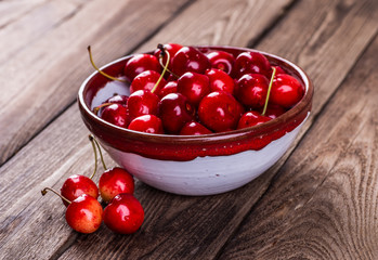 Fresh ripe cherries with jam on a wooden table.