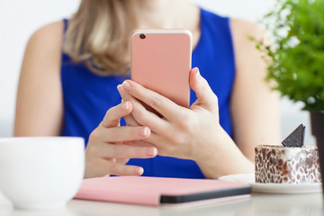 woman in blue dress in the cafe holding pink phone