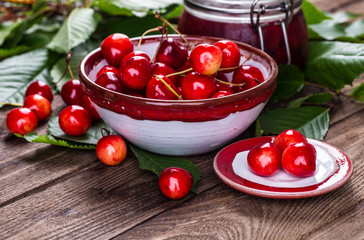 Fresh ripe cherries with jam on a wooden table.