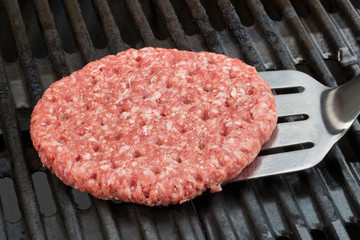 Burgervorbereitung. Ein Burger wird mit einem Bratenwender auf einem Grill gewendet.