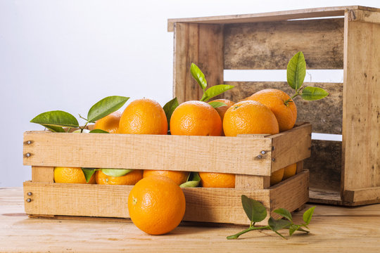 Oranges with leaves in a wooden box.