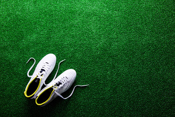 White cleats against green artificial turf, studio shot