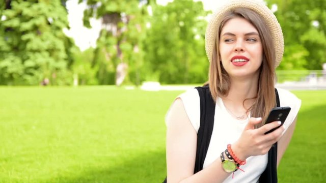 woman with smartphone on green grass with her boyfriend