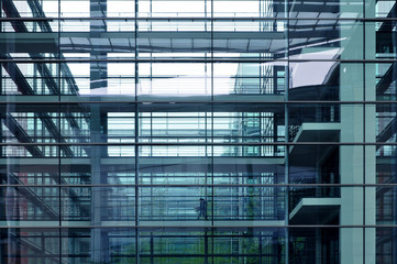 Fototapeta na wymiar The front facade of a modern multistory public building with glass transparent walls. Visible columns and floors. Blue toning