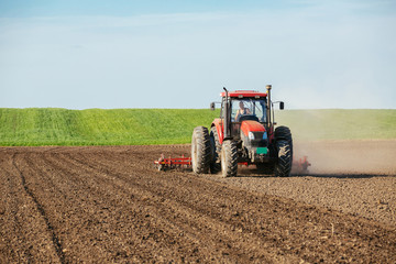 Obraz premium Tractor cultivating field at spring