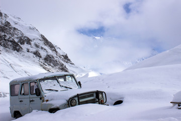 Old russian jeep buried in deep snow in the mountains