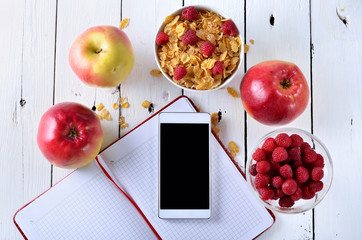 Breakfast of cereals, apples and berries on a wooden table.