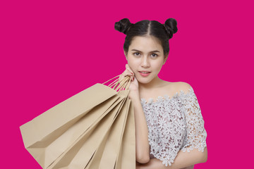 Attractive shopper woman holding shopping bags on pink backgroun