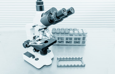 Microscope  and test tubes in laboratory, Blue toned image