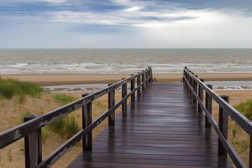 Fototapeta premium Wooden staircase leading into stormy sky and sea at De Haan, Belgium