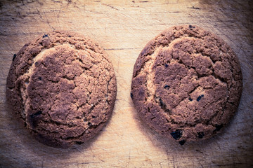 Two dry cookies lie on a wooden board.