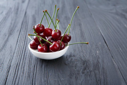 Fresh cherries closeup with green leaves on blue rustic wood