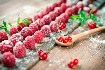 Ripe raspberries with red currants on wooden background