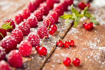 Ripe raspberries with red currants on wooden background
