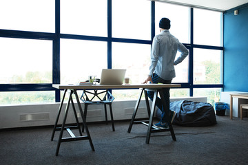 Corporate executive in modern architectural setting looking confidently out of high rise windows