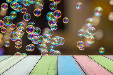 Empty painted wooden table or plank with bokeh of rainbow soap bubbles from the bubble blower on...