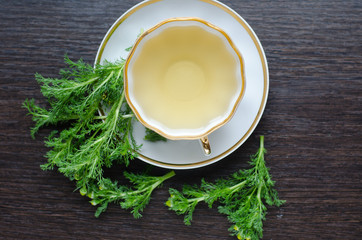 herbal matricaria chamomile tea in a porcelain cup on a dark wooden background