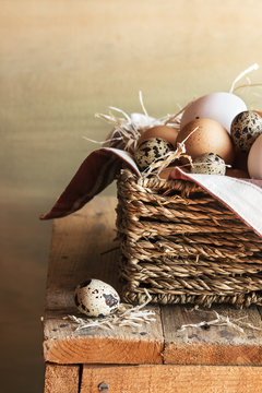 Different kind of raw eggs in a basket on a rustic table