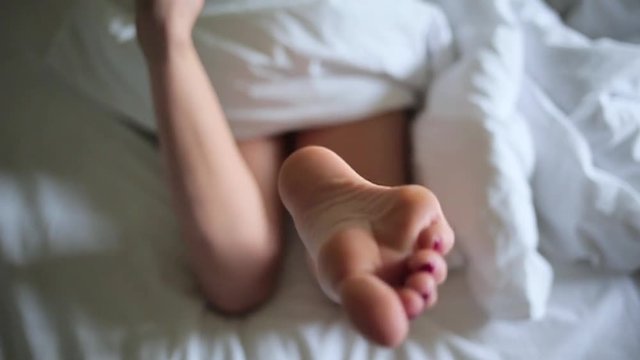 Girl's legs lying in white blanket.