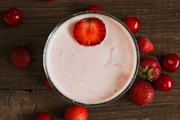 berry smoothie in glass jar on old wooden background. top view