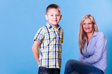 Little boy with mother hold flowers behind back.