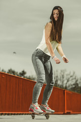 Teen girl skater riding skateboard on street.
