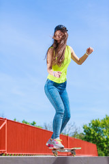 Teen girl skater riding skateboard on street.