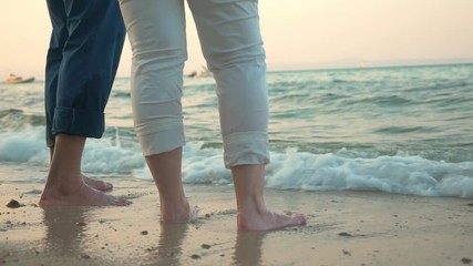 Senior man and woman standing on the beach and sea waves washing their feet - Powered by Adobe