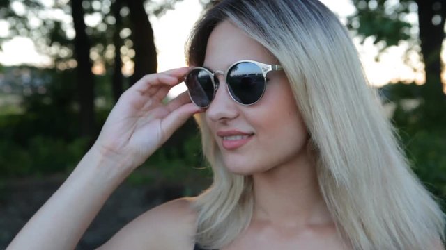 portrait of sexy girl dressing sunglasses and posing at sunset
