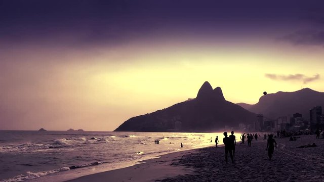 Silhouettes of Brazilians playing altinho keepy uppy beach football at sunset on Ipanema Beach in Rio de Janeiro, Brazil