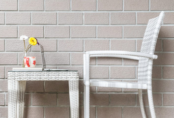 Obraz na płótnie Canvas Closeup artificial colorful flower on glass bottle and computer on wood weave table with wood weave chair on blurred brown brick wall texture background , beautiful interior in relaxation concept