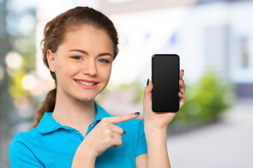 Smiling young woman showing blank smartphone screen