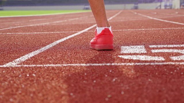 Track runner in red shoes warming up at starting line