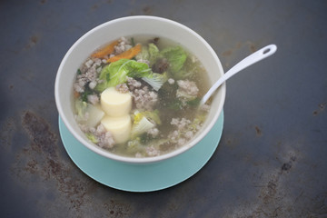 clear soup with bean curd and minced pork and vegetable on steel table, thai traditional food,selective focus, filtered image